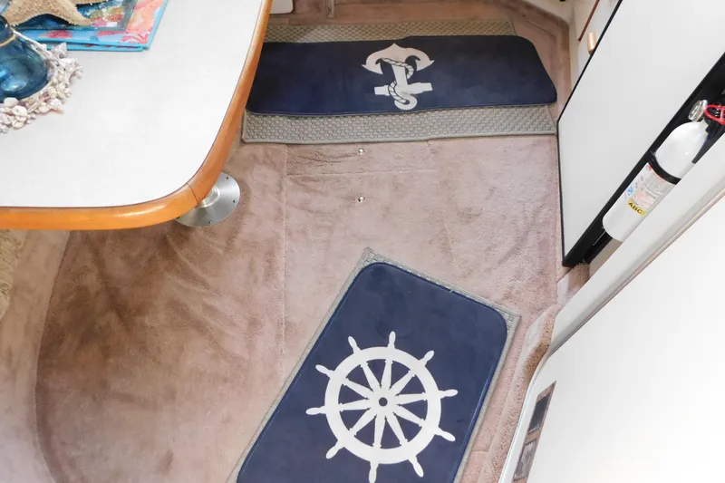 Slide: The Image of Interior of 1990 Sea Ray 350 Express Cruiser with nautical-themed mats and table. - 46