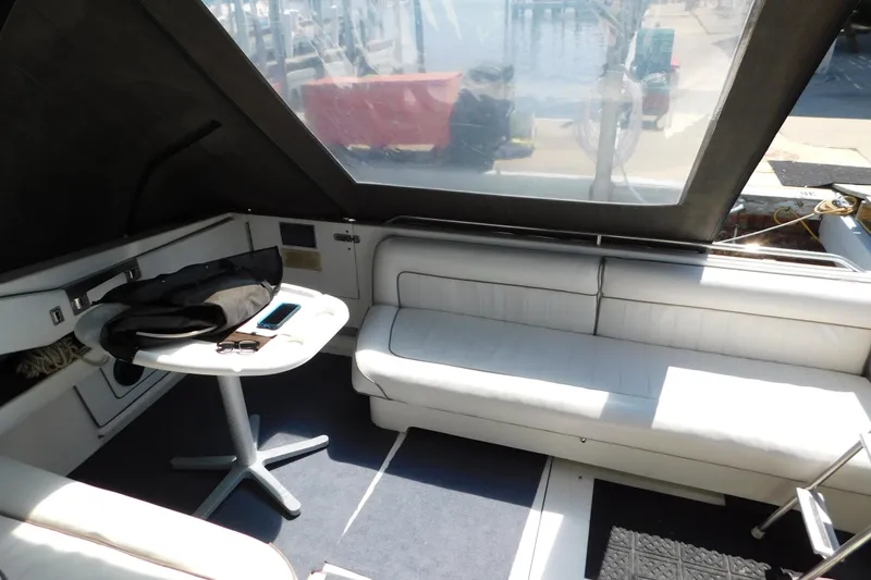 Slide: The Image of Interior of 1990 Sea Ray 350 Express Cruiser with white seating and small table. - 11
