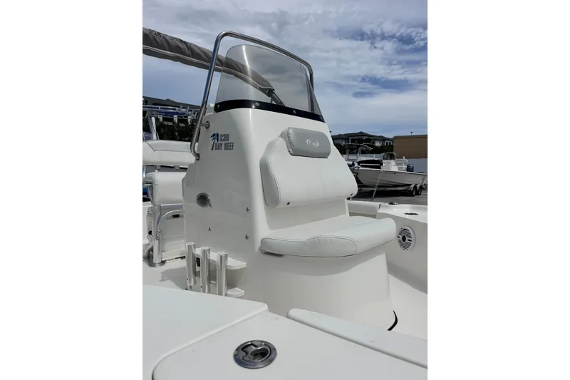 Slide: The Image of 2023 Key West 230 Bay Reef boat interior with seating and console, under a partly cloudy sky. - 8