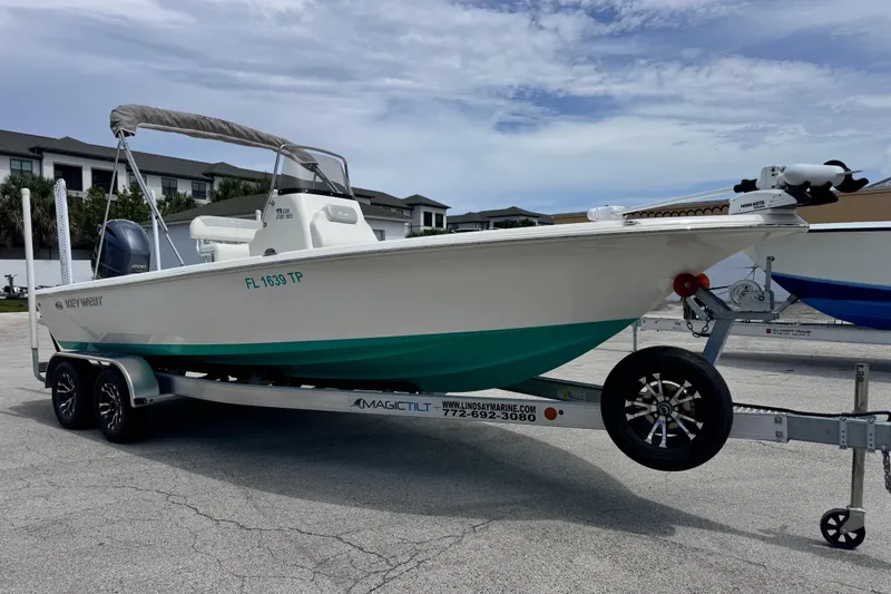 Slide: The Image of 2023 Key West 230 Bay Reef boat on trailer, parked outdoors under cloudy sky. - 6