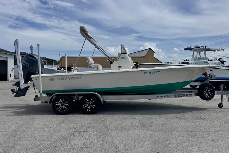 Slide: The Image of 2023 Key West 230 Bay Reef boat on trailer, parked outdoors under a cloudy sky. - 4
