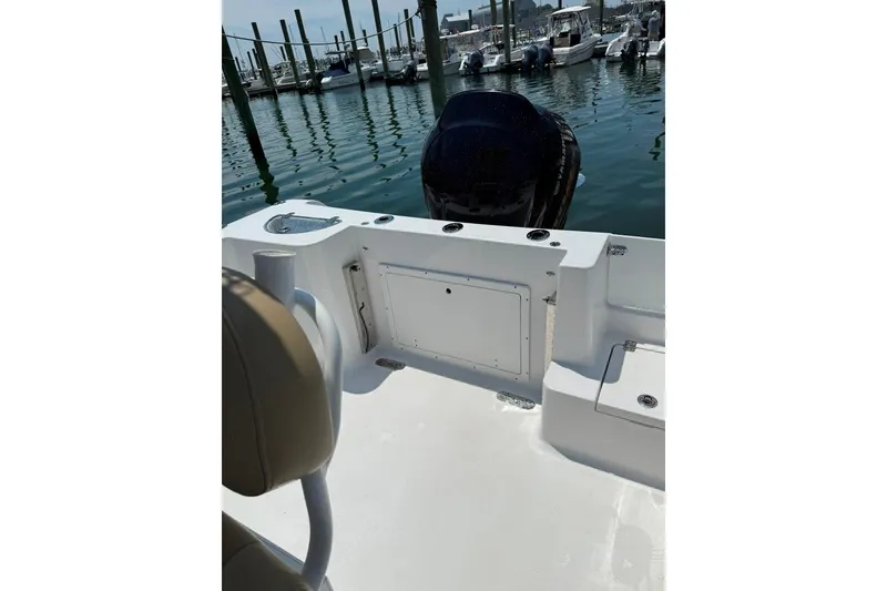 Slide: The Image of 2017 Sportsman Open 232 Center Console boat interior at marina, featuring seating and storage. - 25