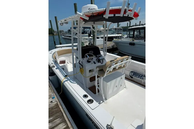 Slide: The Image of 2017 Sportsman Open 232 Center Console boat docked, featuring a T-top and spacious deck. - 4