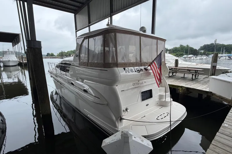 The Image of 2002 Sea Ray 480 Motor Yacht docked, featuring an American flag and covered deck area. - 0