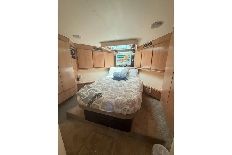Slide: The Image of Cozy bedroom interior of 1995 Hatteras 54 Convertible yacht with wooden cabinetry and plush bedding. - 39