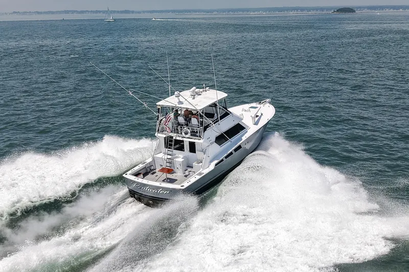 Slide: The Image of 1995 Hatteras 54 Convertible yacht cruising on open water, creating a dynamic wake. - 27