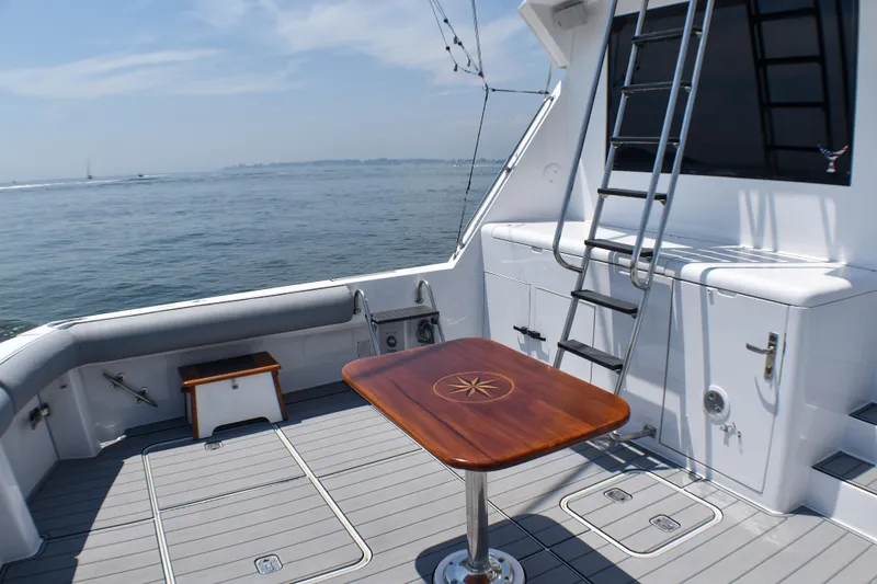 Slide: The Image of Spacious deck of 1995 Hatteras 54 Convertible yacht with wooden table and ocean view. - 19