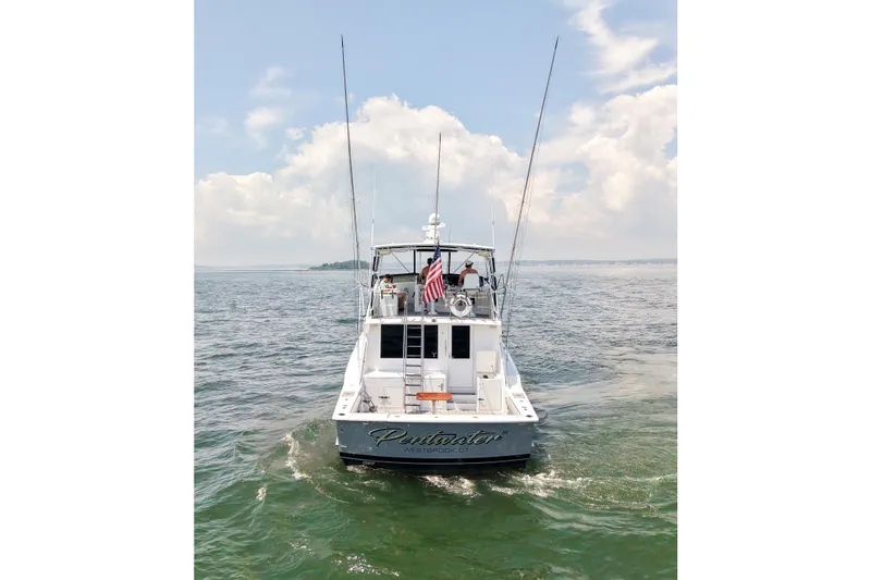 Slide: The Image of 1995 Hatteras 54 Convertible yacht cruising on open water under a partly cloudy sky. - 11