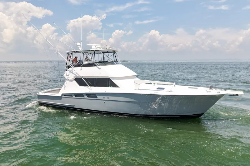 Slide: The Image of 1995 Hatteras 54 Convertible yacht cruising on open water under a clear sky. - 5