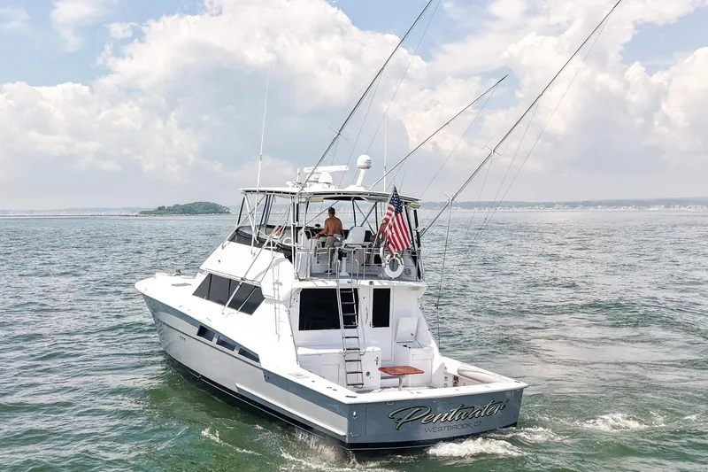 Slide: The Image of 1995 Hatteras 54 Convertible yacht cruising on open water under a cloudy sky. - 7