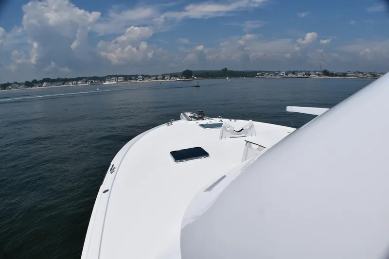 Slide: The Image of 1995 Hatteras 54 Convertible yacht cruising on calm waters under a partly cloudy sky. - 16