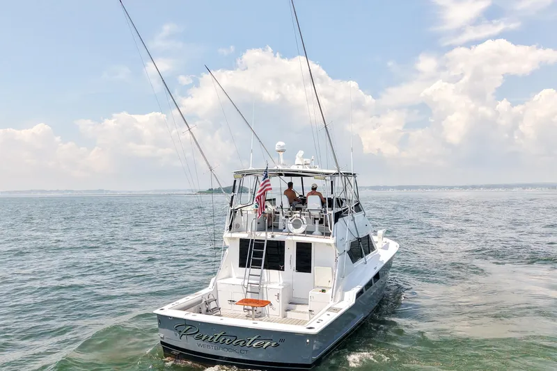 Slide: The Image of 1995 Hatteras 54 Convertible yacht cruising on open water under a cloudy sky. - 10