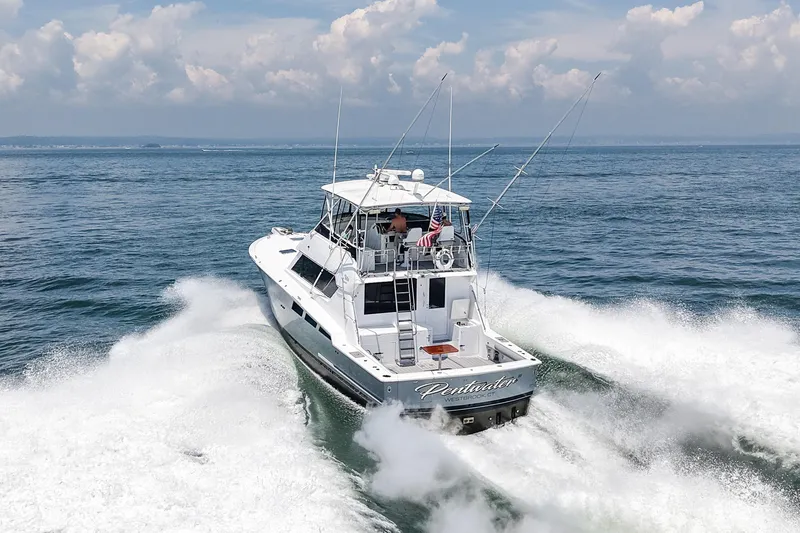 Slide: The Image of 1995 Hatteras 54 Convertible yacht cruising on open water, creating a dynamic wake. - 29