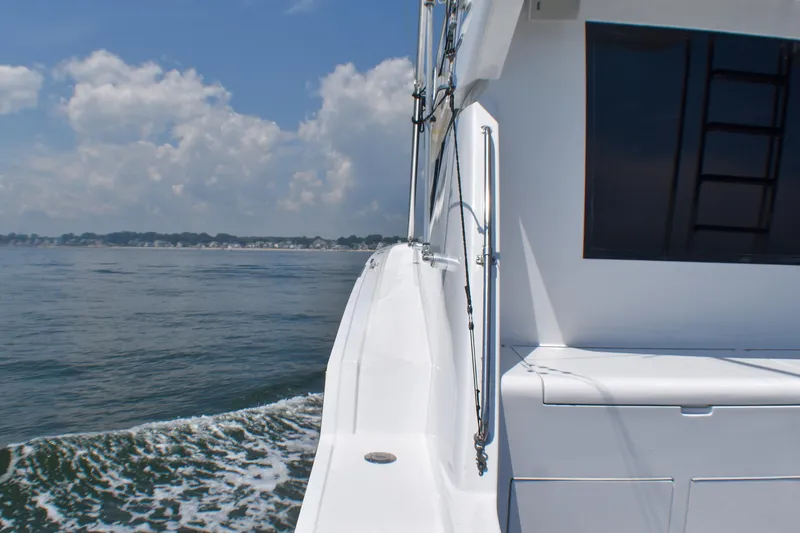 Slide: The Image of 1995 Hatteras 54 Convertible yacht cruising on calm waters under a partly cloudy sky. - 17