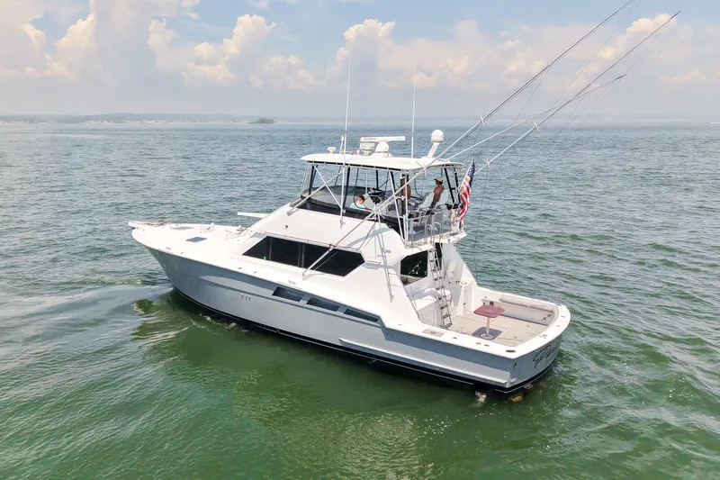 Slide: The Image of 1995 Hatteras 54 Convertible yacht cruising on open water under a partly cloudy sky. - 3
