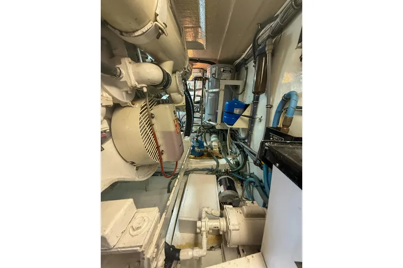 Slide: The Image of Engine room of 1995 Hatteras 54 Convertible yacht, showcasing mechanical components and piping. - 56
