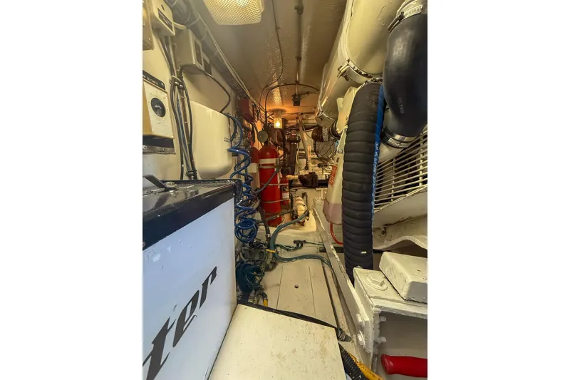 Slide: The Image of Engine room of 1995 Hatteras 54 Convertible yacht with visible equipment and hoses. - 57