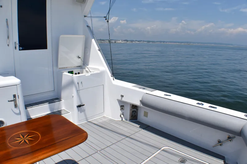 Slide: The Image of 1995 Hatteras 54 Convertible yacht deck with ocean view and wooden table. - 20