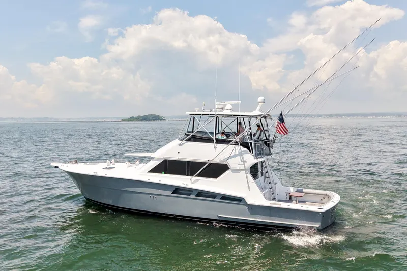 Slide: The Image of 1995 Hatteras 54 Convertible yacht cruising on open water under a cloudy sky. - 4