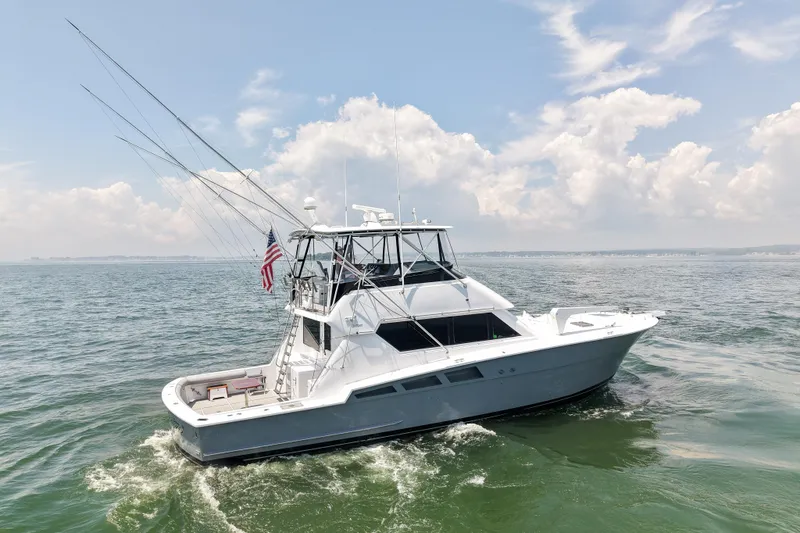 Slide: The Image of 1995 Hatteras 54 Convertible yacht cruising on open water under a partly cloudy sky. - 9