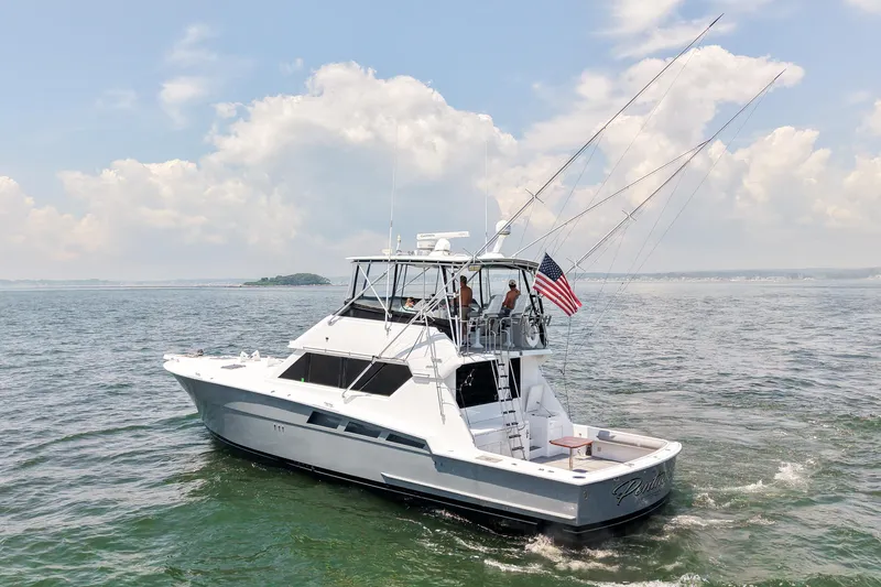 Slide: The Image of 1995 Hatteras 54 Convertible yacht cruising on open water under a partly cloudy sky. - 8