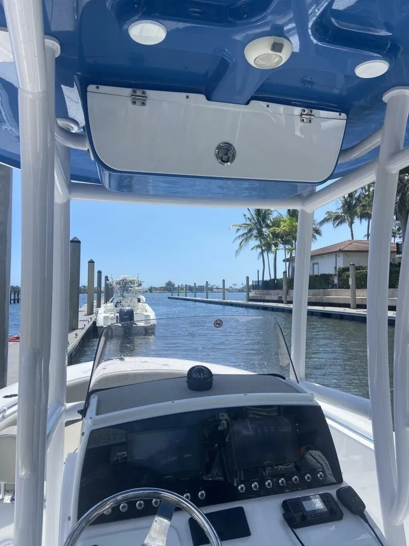 Slide: The Image of 2022 Sportsman Open 232 Center Console boat docked by a scenic waterfront. - 19