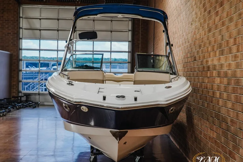 Slide: The Image of 2011 Chaparral 246 SSi boat in indoor storage, featuring a sleek design and blue canopy. - 4