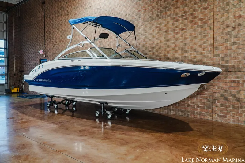 Slide: The Image of 2011 Chaparral 246 SSi boat with blue hull and canopy, displayed indoors at Lake Norman Marina. - 3