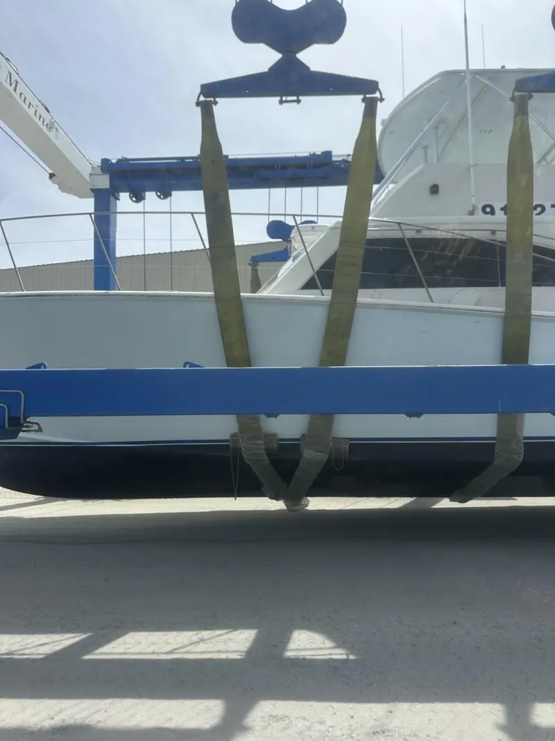 Slide: The Image of 1987 Miller Sportfish 55 yacht in dry dock, secured with straps for maintenance. - 12