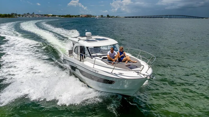 Slide: The Image of A 2021 Beneteau Antares 11 speeds across the water with two people on board. - 17