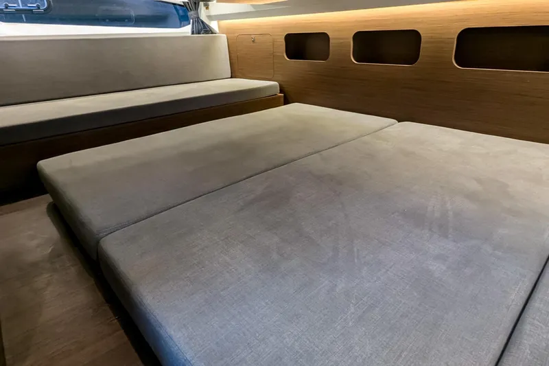Slide: The Image of 2021 Beneteau Antares 11 interior with convertible seating and modern wood paneling. - 12