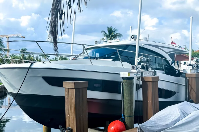 Slide: The Image of 2021 Beneteau America Antares 11 yacht docked by palm trees and water. - 2