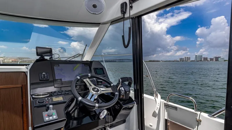 Slide: The Image of The cockpit of a Beneteau Antares 11 overlooking the water and city skyline. - 18