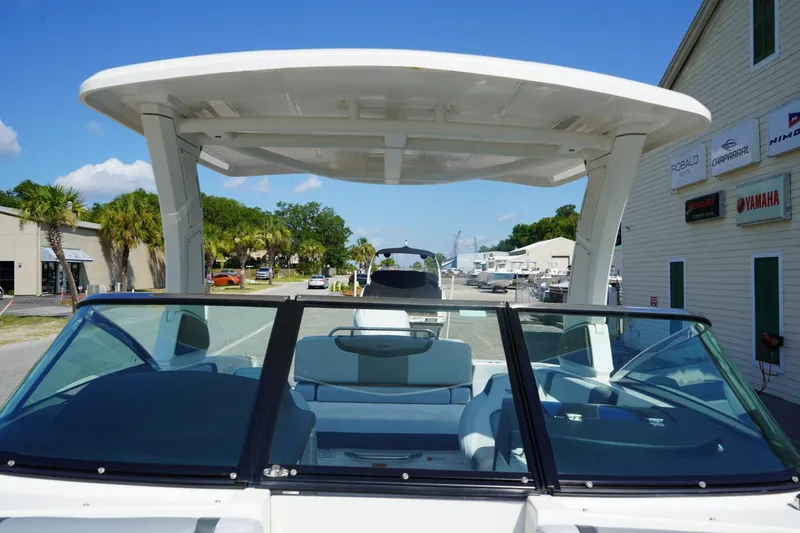 Slide: The Image of 2025 Chaparral 270 OSX boat with sleek design, docked near dealership signs. - 13