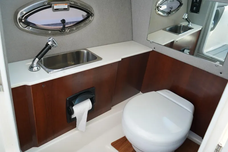Slide: The Image of 2025 Chaparral 270 OSX boat bathroom with sink, toilet, and mirror. - 5
