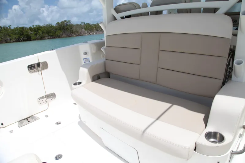 Slide: The Image of 2019 Boston Whaler 380 Outrage boat seating area with beige cushions and cup holders. - 16