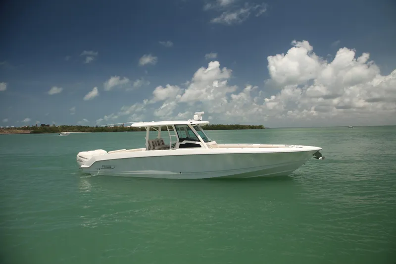 The Image of 2019 Boston Whaler 380 Outrage boat on calm turquoise water under a partly cloudy sky. - 0