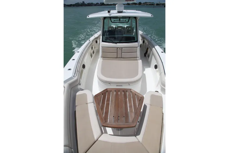 Slide: The Image of 2019 Boston Whaler 380 Outrage boat with spacious seating and wooden table on deck. - 18