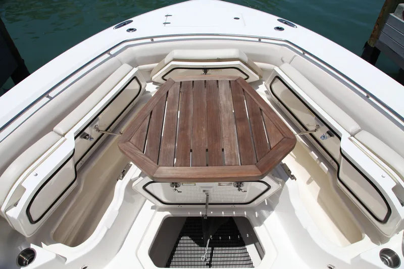 Slide: The Image of 2019 Boston Whaler 380 Outrage boat interior with wooden table and cushioned seating. - 56