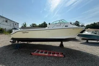 Slide: The Image of 2003 Edgewater 265 Express boat on gravel lot under clear sky. - 34