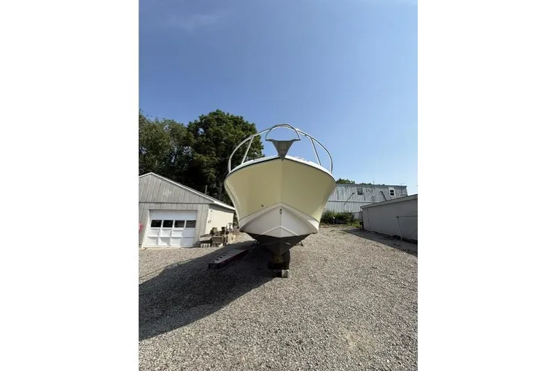 Slide: The Image of 2003 Edgewater 265 Express boat on gravel lot under clear blue sky. - 4