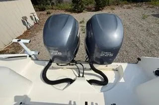 Slide: The Image of Twin outboard engines on a 2003 Edgewater 265 Express boat, parked on gravel. - 23
