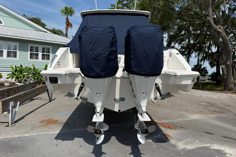 Slide: The Image of 2024 Pursuit DC 306 Dual Console boat with covered engines, parked outdoors. - 5