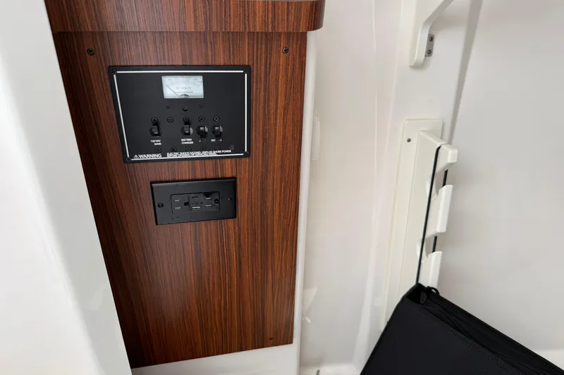 Slide: The Image of 2024 Pursuit DC 306 Dual Console electrical panel with wood finish and power outlets. - 32