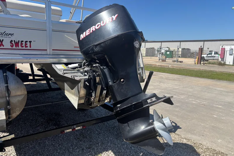 Slide: The Image of 2008 Sun Tracker Fishin' Barge 21 with Mercury outboard motor, parked on a trailer. - 3