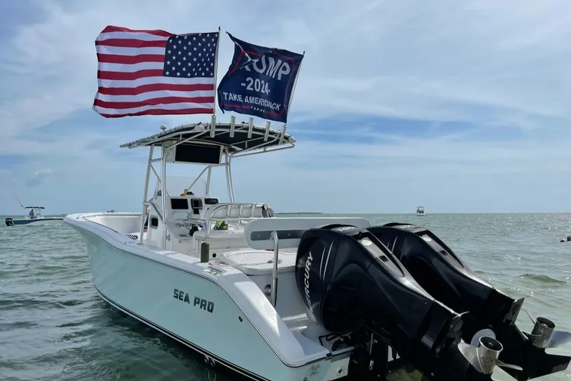 Slide: The Image of 2007 Sea Pro 270 Center Console boat with flags, dual Mercury engines, on calm water. - 2