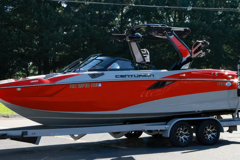 Slide: The Image of 2024 Centurion Fi23 boat in vibrant red on a trailer, parked outdoors. - 18