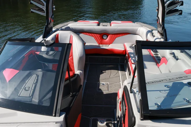 Slide: The Image of 2024 Centurion Fi23 boat interior with red and gray seating, open windshield, on calm water. - 14