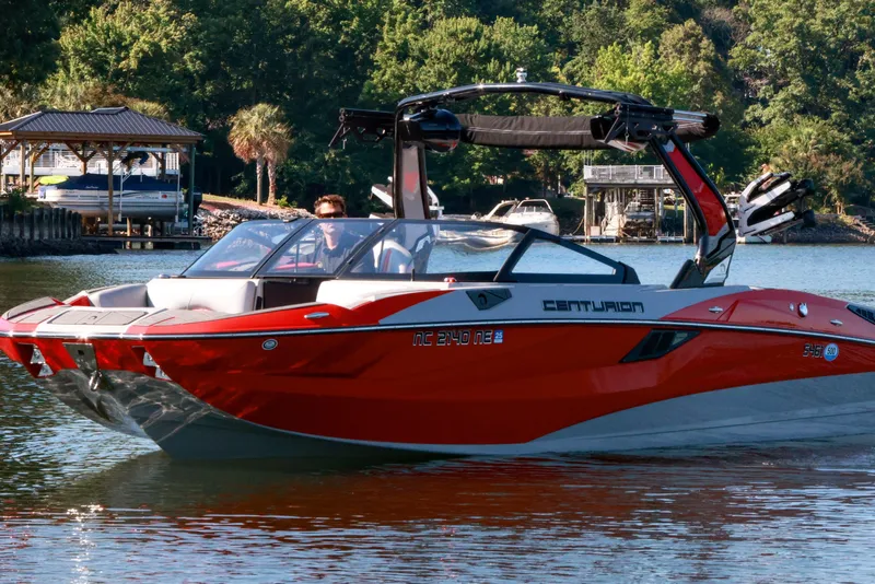 Slide: The Image of 2024 Centurion Fi23 boat cruising on a serene lake with lush greenery in the background. - 5