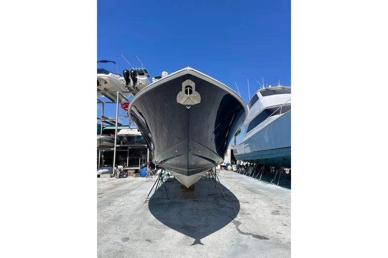 Slide: The Image of 2025 Jupiter 43 boat in dry dock, viewed from the front under a clear blue sky. - 2